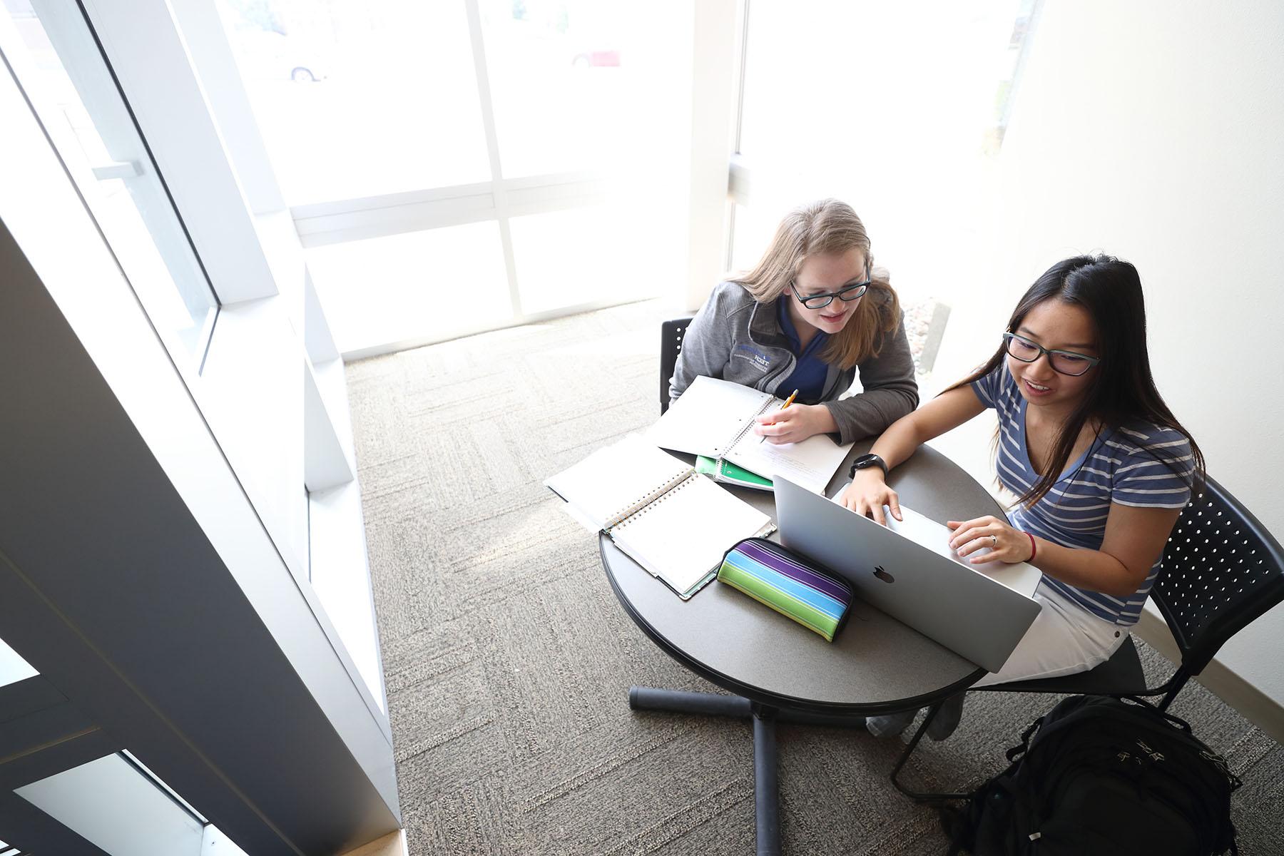 Students in sunny study area with large windows